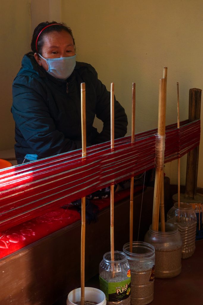 Sanghi Thema in front of her makeshift loom.