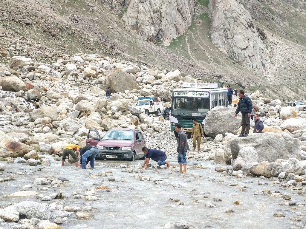 People helping the vehicles out of the stream. It is advisable to ride a vehicle with good tyre clearance.