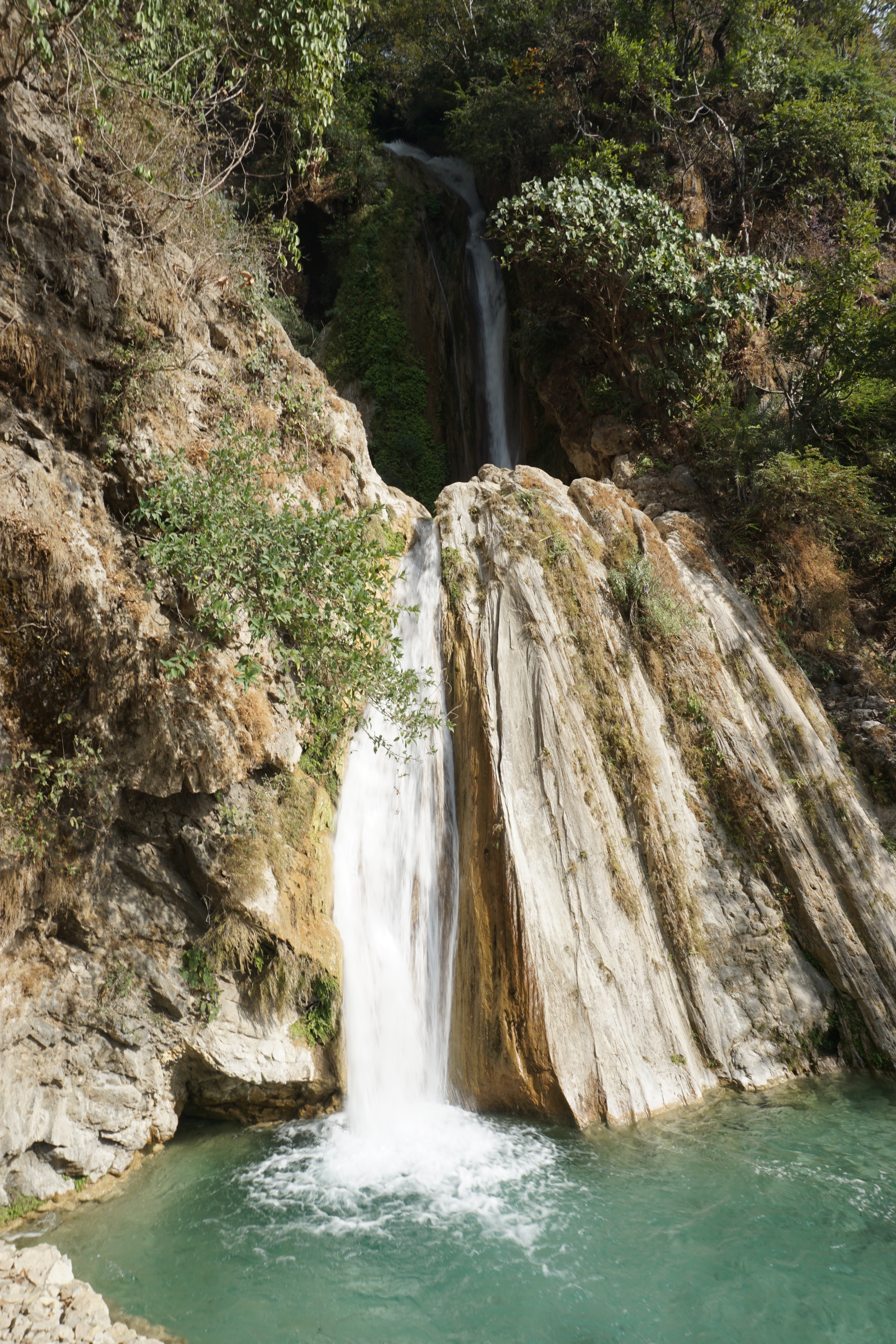 The Neer Garh waterfall emerges out of a small cave and collects in a man-made pool below before flowing down.