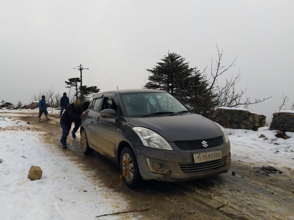 BRO (GREF) workers pushing another hatchback on icy roads.