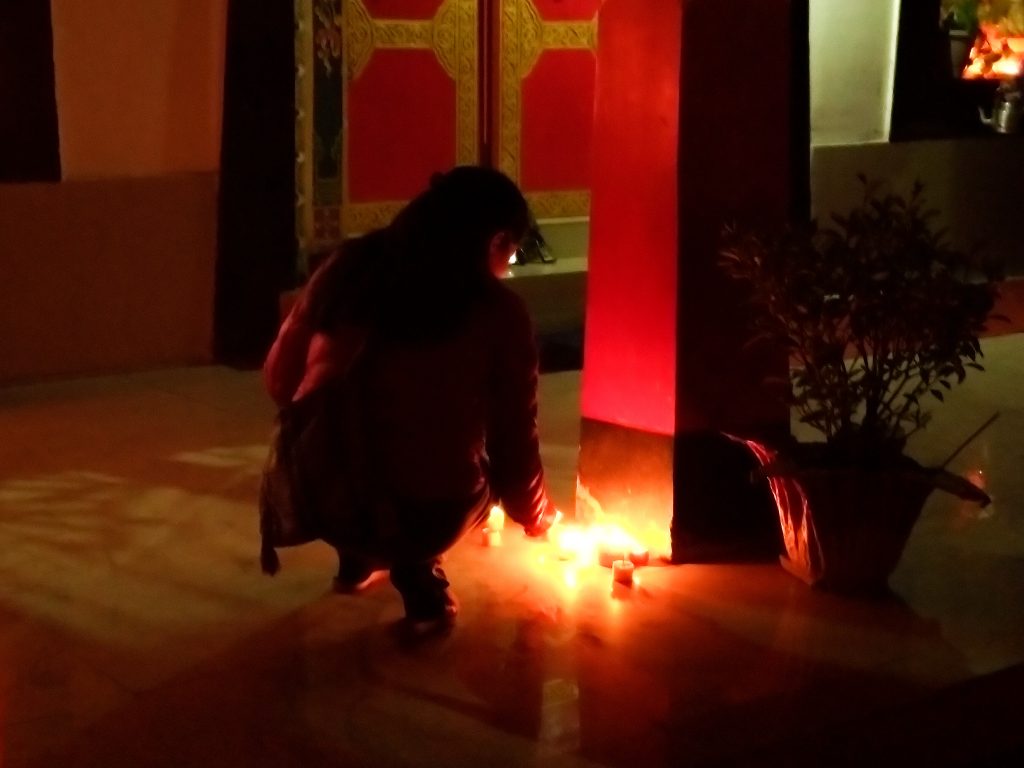 A local lighting candles on the courtyard of the Gompa.