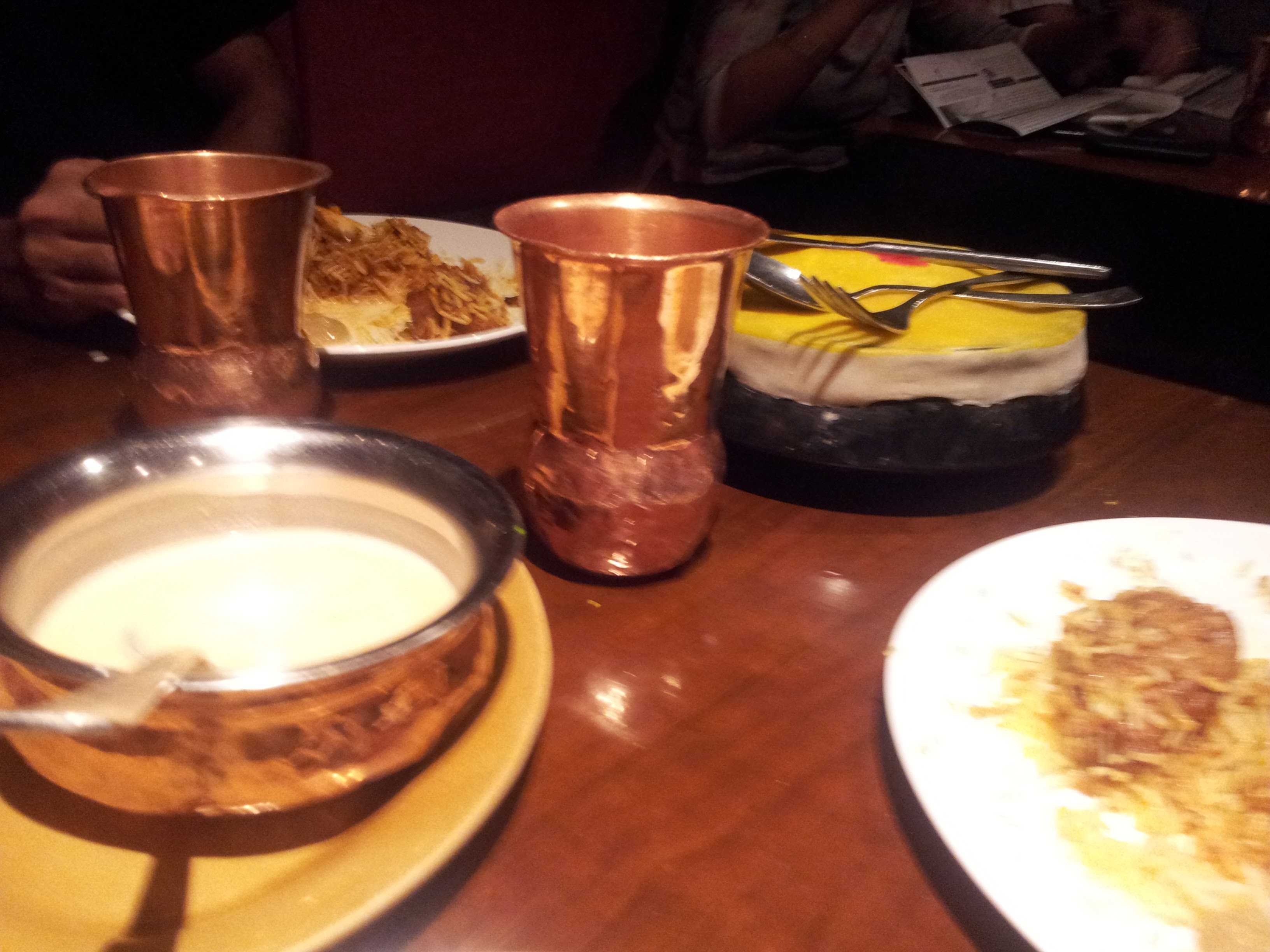 Biriyani on plates and inside the earthen handi. The biriyanis are accompanied by salan and raita.
